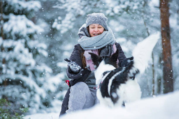 istock Woman playing with dog in snowy forest 1063735716