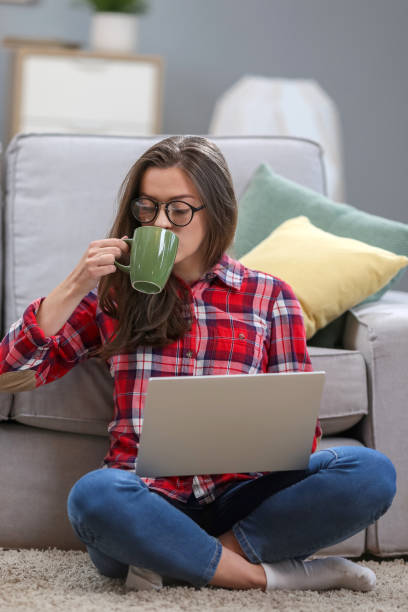 istock Portrait of a smiling female  in glasses using laptop computer while relaxing on a couch at home. 1063736138