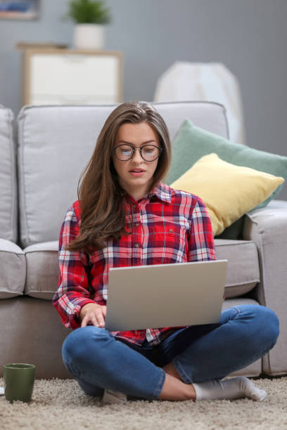 istock Portrait of a smiling female  in glasses using laptop computer while relaxing on a couch at home. 1063736232