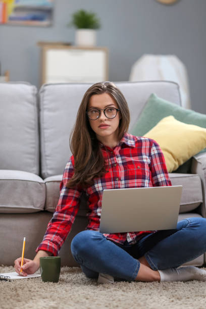 istock Portrait of a smiling female  in glasses using laptop computer while relaxing on a couch at home. 1063736234