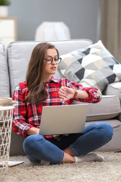 istock Portrait of a smiling female  in glasses using laptop computer while relaxing on a couch at home. 1063736274