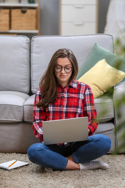 istock Portrait of a smiling female  in glasses using laptop computer while relaxing on a couch at home. 1063736306
