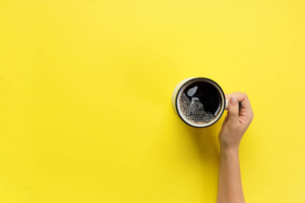bras femmes tenir la tasse de café sur fond jaune. vue de dessus avec espace de cope - high angle view people people in a row directly above photos et images de collection