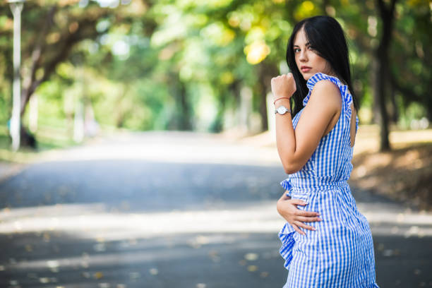 Young woman in a striped dress posing in public park