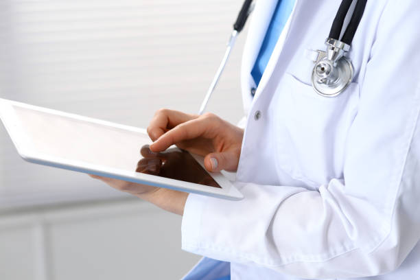 istock Woman doctor using white tablet computer while working in hospital, close-up. 1063739800