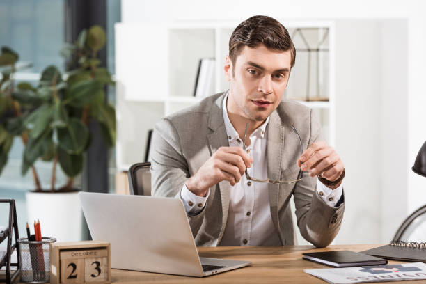 istock handsome businessman with eyeglasses looking at camera at office 1063755152