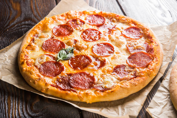istock Small mini pizza (mini, miniature) on baking paper on a dark wooden background 1063755642