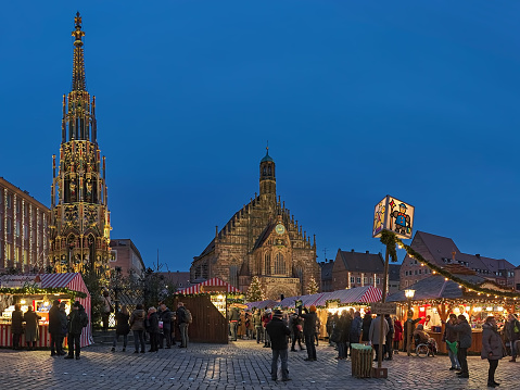 Nuremberg, Germany - December 13, 2017: Christkindlesmarkt at Hauptmarkt platz (Main Market Square) in dusk. Unknown people walk around the market stalls. This is one of the largest Christmas markets in Germany and one of the most famous in the world. The market started back in the 17th century.
