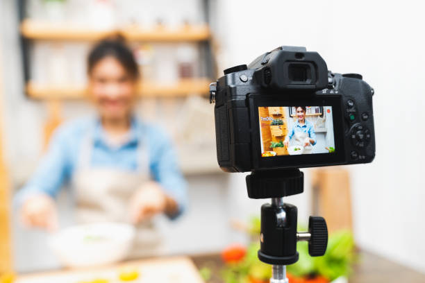 blogger asiáticos bonito jovem garota gravação vídeo sessão tutorial de salada, aula de culinária na cozinha de casa. comida blogging, passatempo de mídia social de radiodifusão, ou conceito de curso de aprendizagem on-line - women home video camera camera vitality - fotografias e filmes do acervo