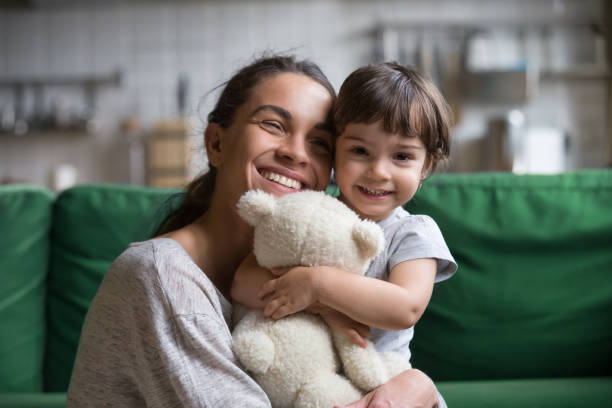 smiling single young mum embracing little daughter - child offspring women posing imagens e fotografias de stock