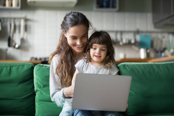счастливый смех матери и дочери с помощью ноутбука - laptop women sofa internet стоковые фото и изображения
