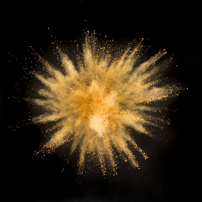 Gold powder explosion on black background. Freeze motion.