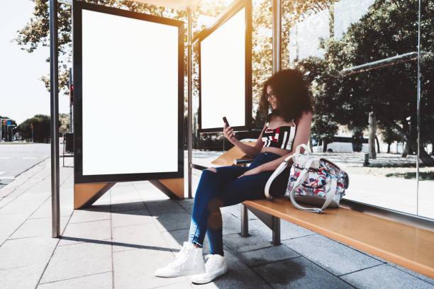 Girl with smartphone and two billboard templates in bus stop