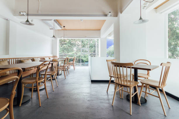 un minimum de pain café décorer avec mur blanc et des chaises en bois. chaleureux, accueillant et confortable. - café établissement de restauration photos et images de collection