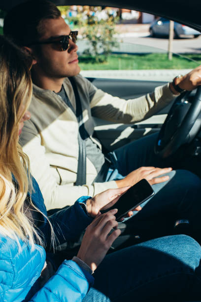istock woman using smartphone with blank screen while boyfriend driving car 1063777960