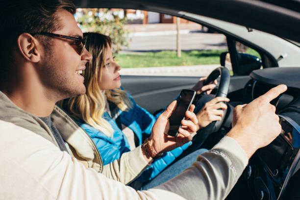 istock smiling man with smartphone showing direction to girlfriend that driving car 1063779046