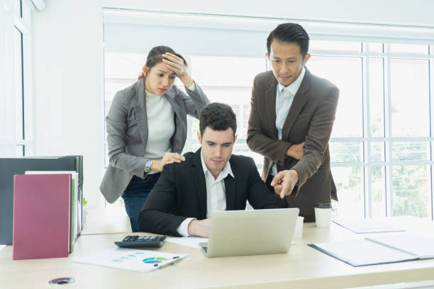 istock business, teamwork, people and crisis concept. business team sitting  solving problem in office. businessmen and women serious argument negative emotion . 1063780320