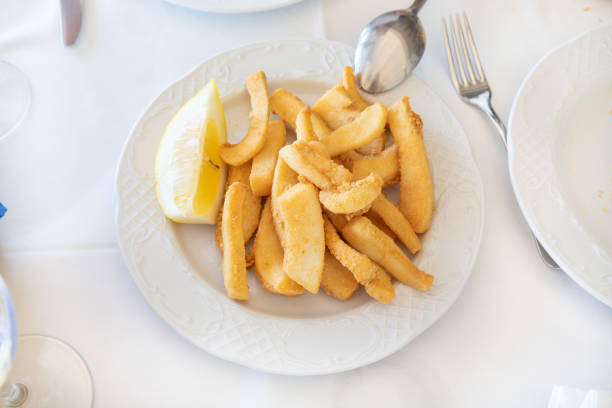 aerial view of white circular plate with sepia or squid breaded and fried, typical food of Andalusia in Spain Europe on white tablecloth ready to serve