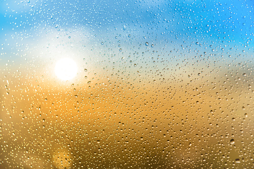 Beautiful sunset through a spattered glass with water rain drops