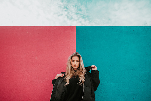 A young woman with winter clothes over a colorful wall