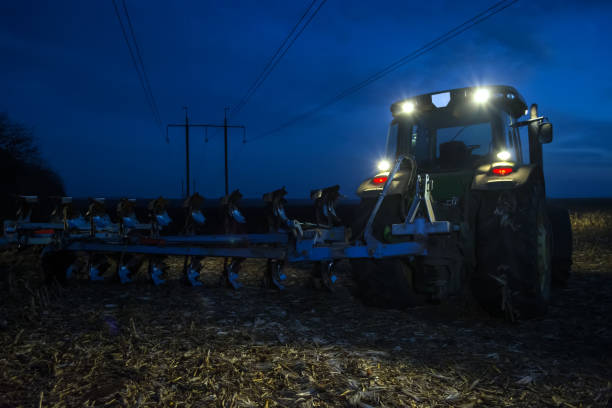 istock two tractor plowing the land late at night with the headlights on 1063786272
