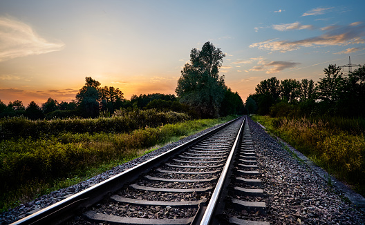 Líneas de ferrocarril enfrente de la naturaleza y la puesta del sol photo