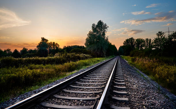 líneas de ferrocarril enfrente de la naturaleza y la puesta del sol - transporte ferroviario fotografías e imágenes de stock