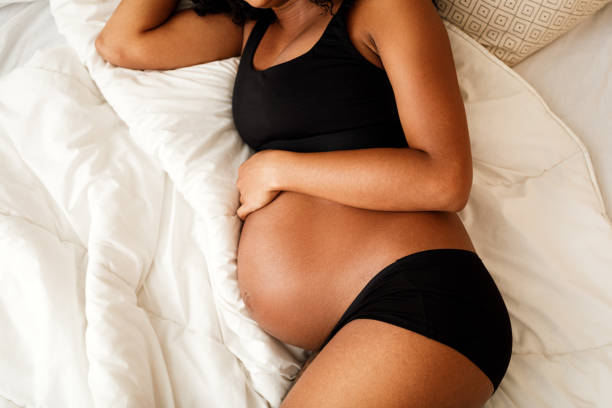 Unrecognizable pregnant woman lying on a bed stock photo
