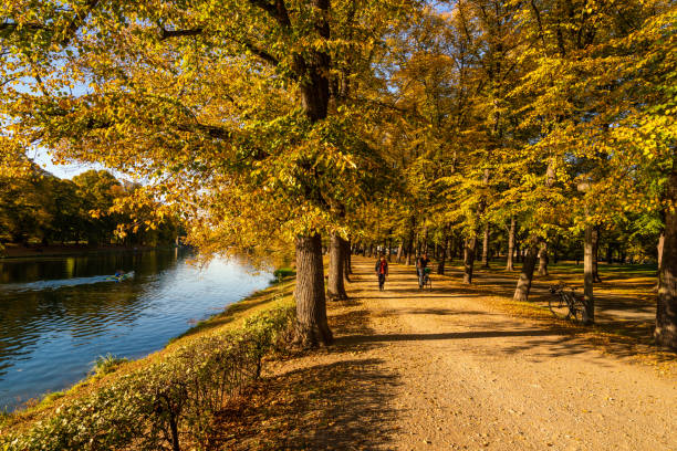 Leipzig, Germany - October 12, 2018: Leipzig  view showing Autumn trees, people riding boat in river elster and walking on the road bicycle can be seen on the background