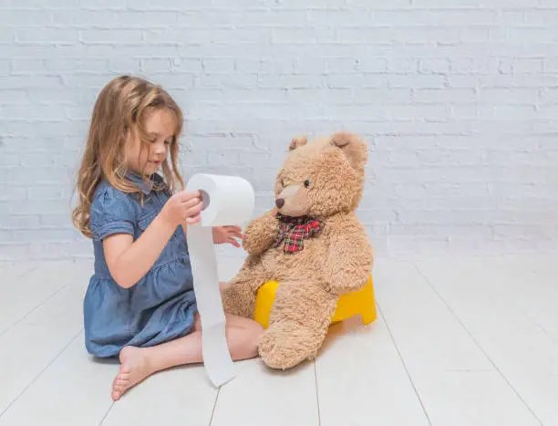 Photo of Little Girl Learning Potty Training with a Teddy Bear