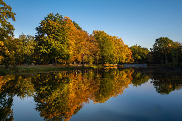 Leipzig, Germany - October 12, 2018: Leipzig  view showing Autumn trees, people riding boat in river elster and walking on the road bicycle can be seen on the background