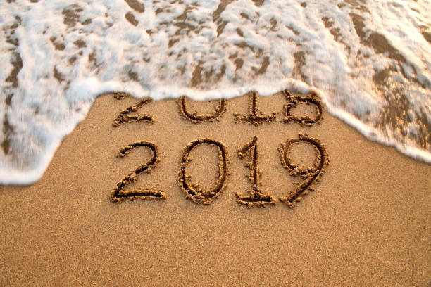 istock New year 2019 and 2018 on sandy beach with waves 1063807894