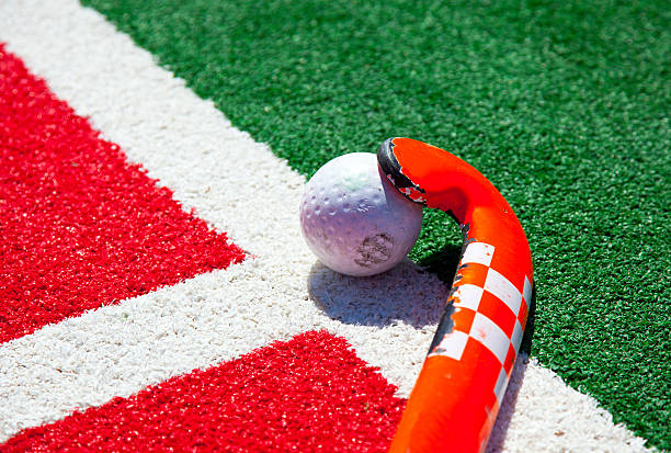 Red and white hockey stick with white ball on the ground hockey stick on the field field hockey stock pictures, royalty-free photos & images