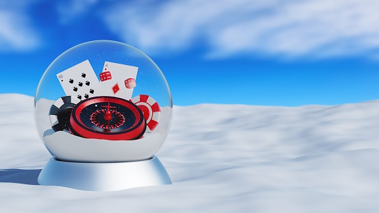 Christmas snow globe with roulette, cards and poker chips inside on a silver base - winter landscape