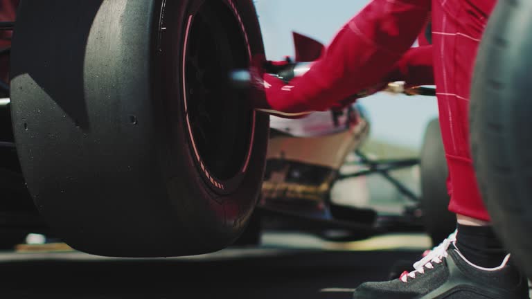 Mechanic fastening tire of racecar at pit stop