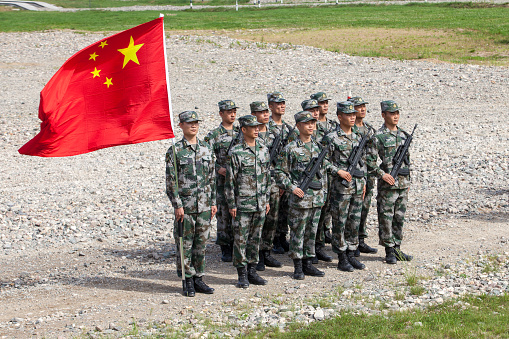 Pesochnoye village, Kostroma region, Russia - June 10, 2018. Great military games Army Games 2018. \nThe country participants of the games Iran Kazakhstan Belarus China Armenia Russia Egypt \nOne of the stages is a safe environment (international competitions among military units of chemical and bacteriological protection)\n a platoon of Chinese soldiers with the flag of the Chinese People`s Republic