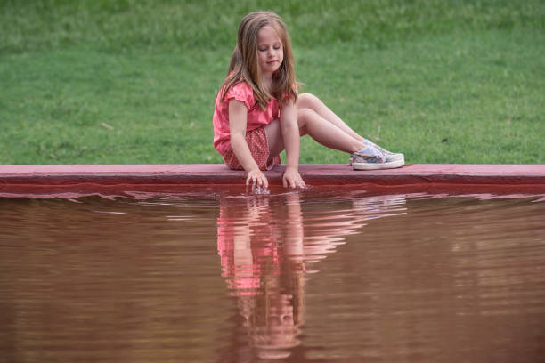 A 5 year old child in pink shirt and her reflection in fountain