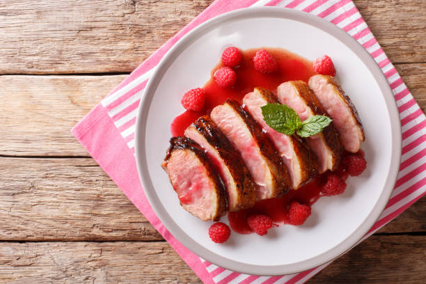 istock Tasty honey duck breast with raspberry sauce and mint on a plate on the table. horizontal top view 1063820040