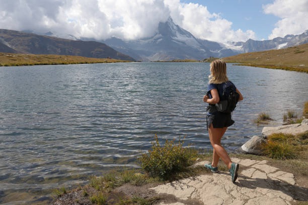 istock Female hiker walks up to lake edge 1063820800