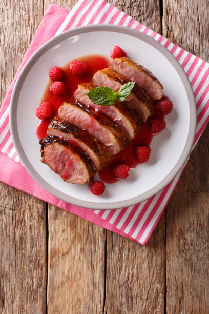 istock Tasty honey duck breast with raspberry sauce and mint on a plate on the table. Vertical top view 1063820840