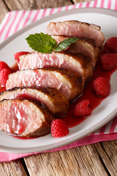 istock Sliced fried duck breast with fresh raspberry sauce and mint closeup on a plate. vertical 1063821464