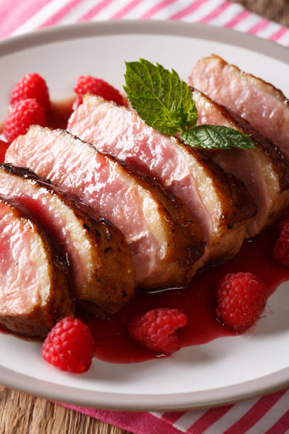 istock natural food: fried duck breast served with fresh raspberry sauce and mint closeup on a plate. vertical 1063821500