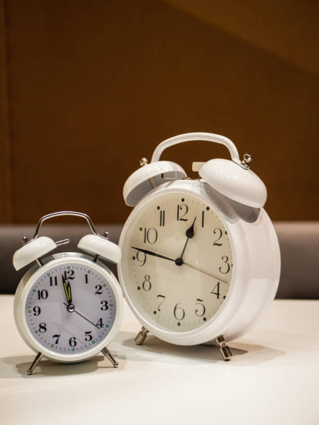 istock Vintage Alarm Clocks standing on a white desk with brown blurry background 1063821530
