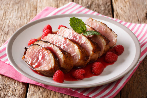 istock festive food: sliced grilled duck breast with raspberry sauce and mint closeup on a plate on the table. horizontal 1063821564