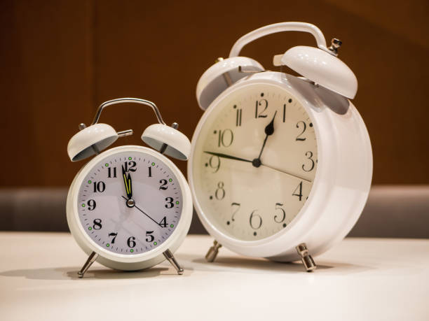 istock Vintage Alarm Clocks standing on a white desk with brown blurry background 1063822250
