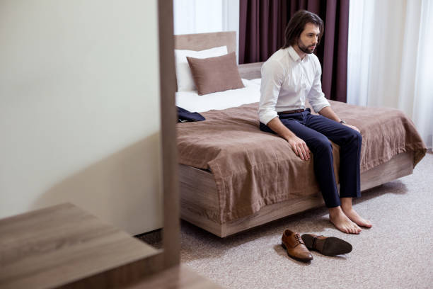 istock Sad tired man sitting on the bed in the hotel 1063822488