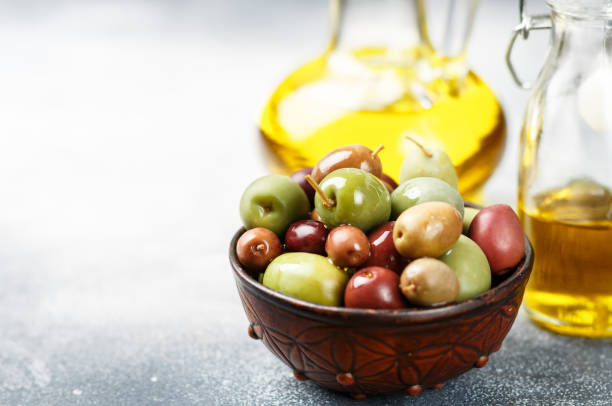 istock Mixed marinated olives (green, black and purple) in ceramic bowl  and olive oil 1063822976