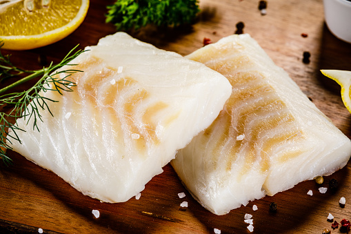 Fresh raw cod on stone cutting board background