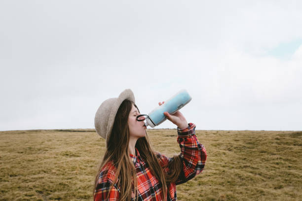 istock Woman in hat drinking water in the mountains 1063828978