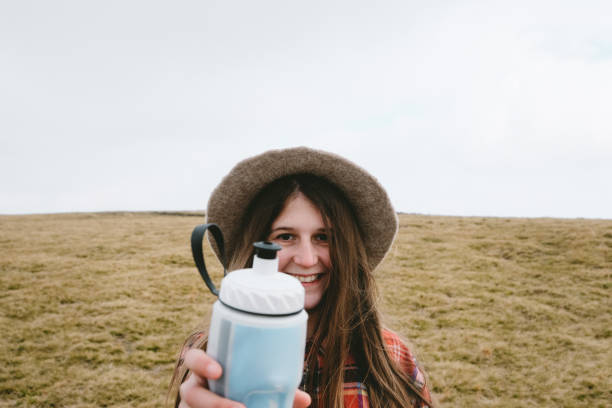 istock Woman in hat drinking water in the mountains 1063829536